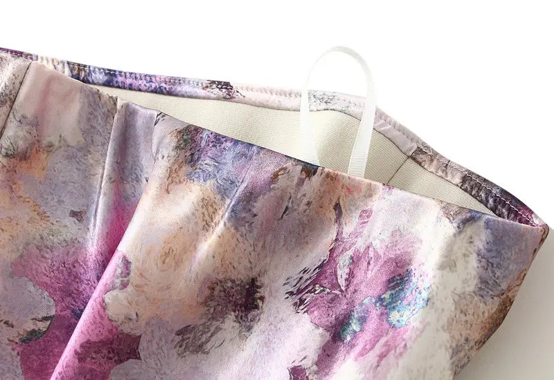 Ein floraler Satin-Midirock mit hoher Taille mit einer weichen, fließenden Gestaltung und einem lebendigen abstrakten Blumenmuster in Farbtönen von Pink, Violett und Beige.