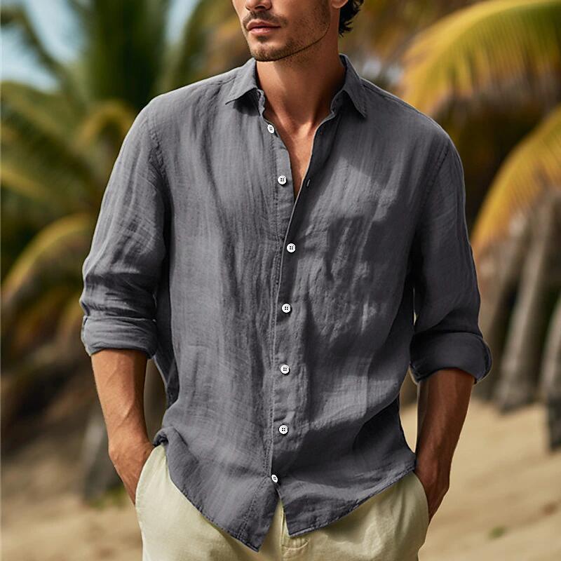 A man wearing a dark gray men’s relaxed fit cotton linen long sleeve shirt with rolled-up sleeves and white buttons.