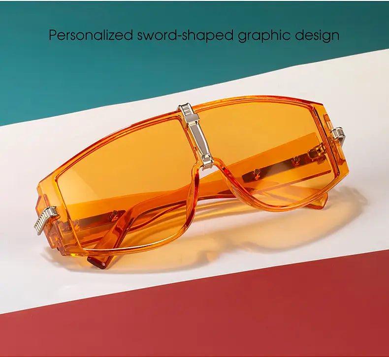 Vintage Shield UV400 futuristic oversized sunglasses featuring orange-tinted transparent plastic lenses with bold sword-shaped graphic design and metallic silver accents.