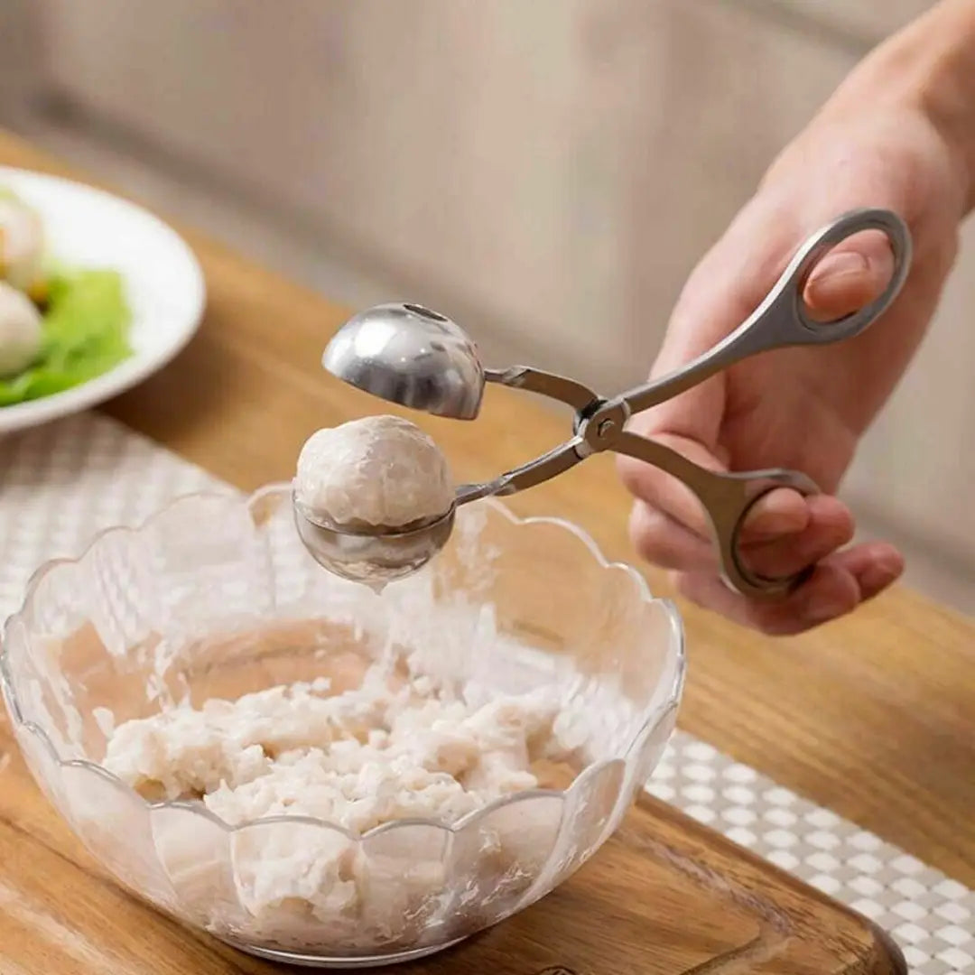Stainless steel meatball maker tongs with rounded spherical molds and ergonomic handles designed for kitchen use.