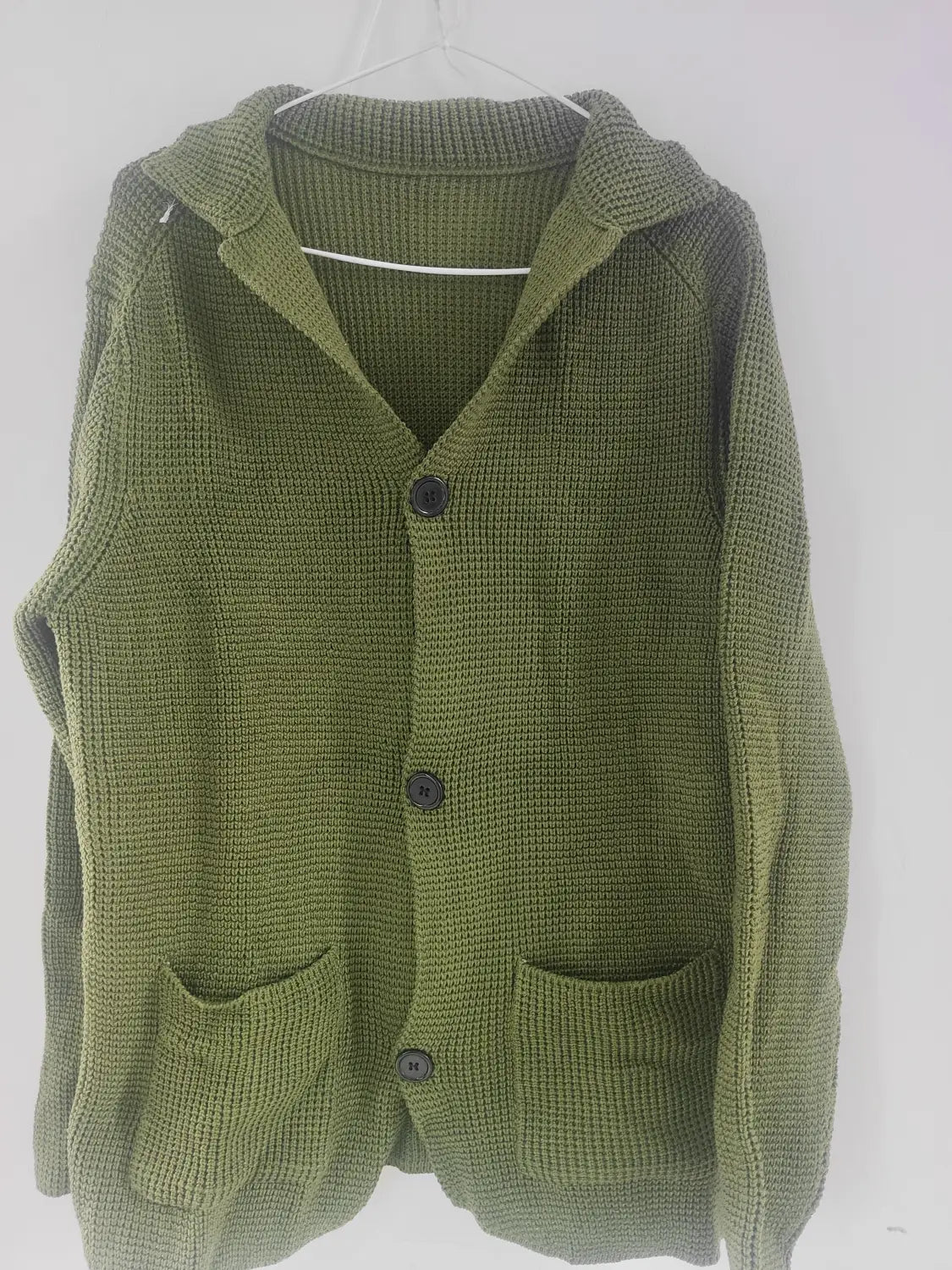 Cardigan à capuche tricoté vert olive pour homme, avec trois boutons gris foncé et deux poches avant, conçu comme un pull à col montant.