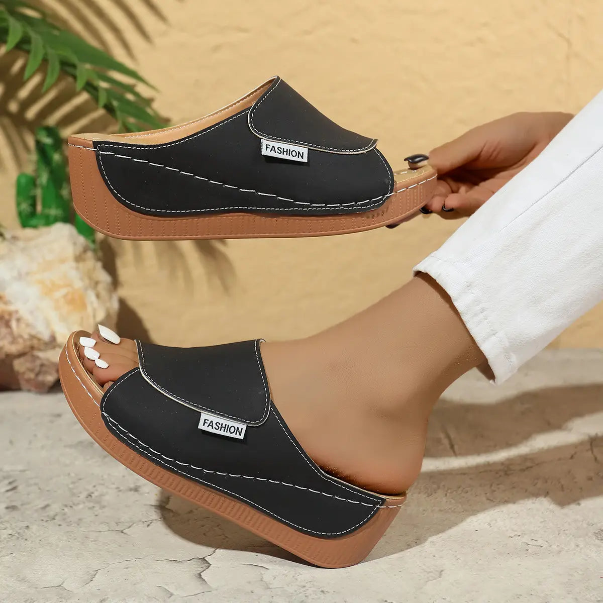 Mules à plateforme compensée à bride glissante pour femmes noires avec des semelles camel, des coutures blanches et une étiquette de mode sur le côté