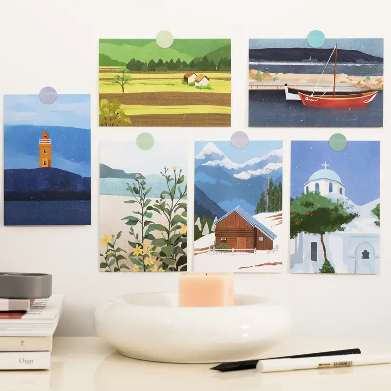Set of six illustrated travel diary winter postcards featuring vibrant landscapes including a lighthouse, fields with houses, and snowy cabins for wall decor.