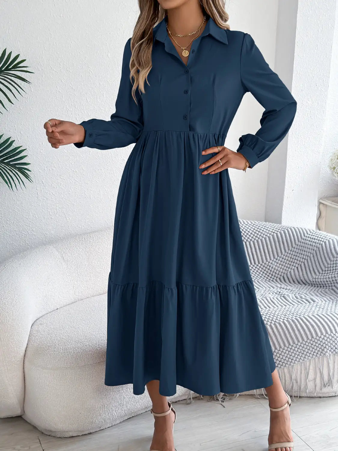 A navy blue women’s long sleeve tiered button down midi dress with a collar and a flowy skirt.