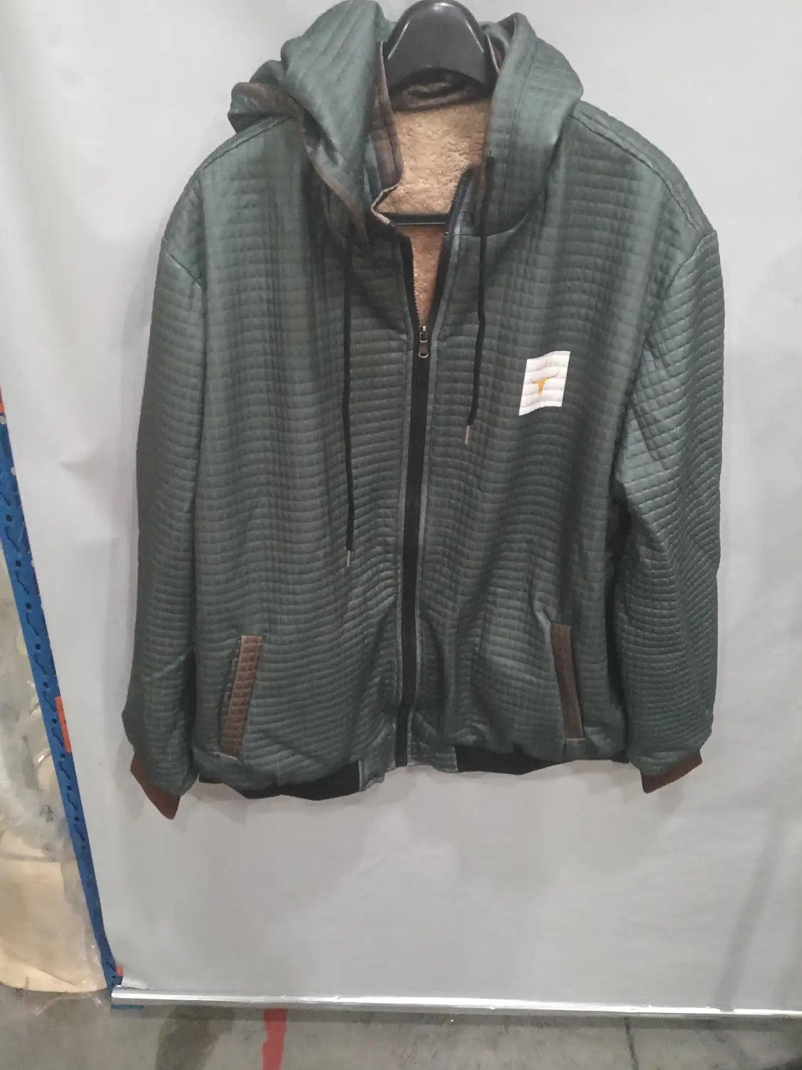 Veste à capuche zippée doublée de polaire pour homme en tissu matelassé vert foncé, intérieur en polaire et fermeture éclair noire.