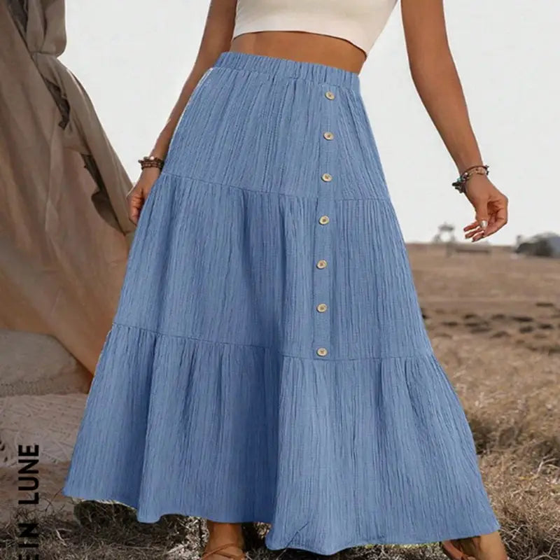 Light blue tiered maxi skirt with pleated texture and button front closure designed for lightweight casual wear.