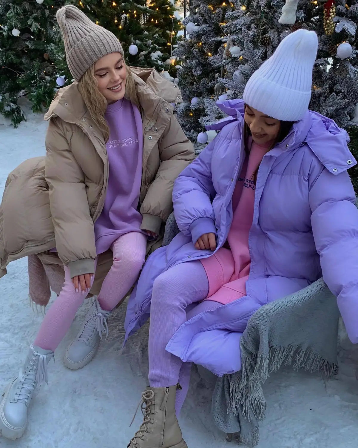 Deux femmes portant des doudounes d’hiver matelassées à capuche pour femme en beige et violet éclatant, associées à des leggings et des pantalons confortables.