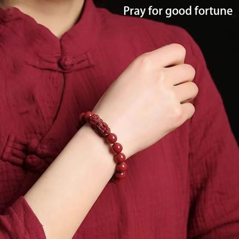 a hand carved purple gold cinnabar double pixiu bracelet featuring a red carved dragon bead worn on a wrist