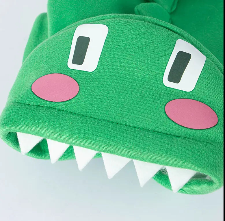 Green plush dinosaur cat hoodie pet costume hat featuring white eyes pink cheeks and a row of white triangular teeth.