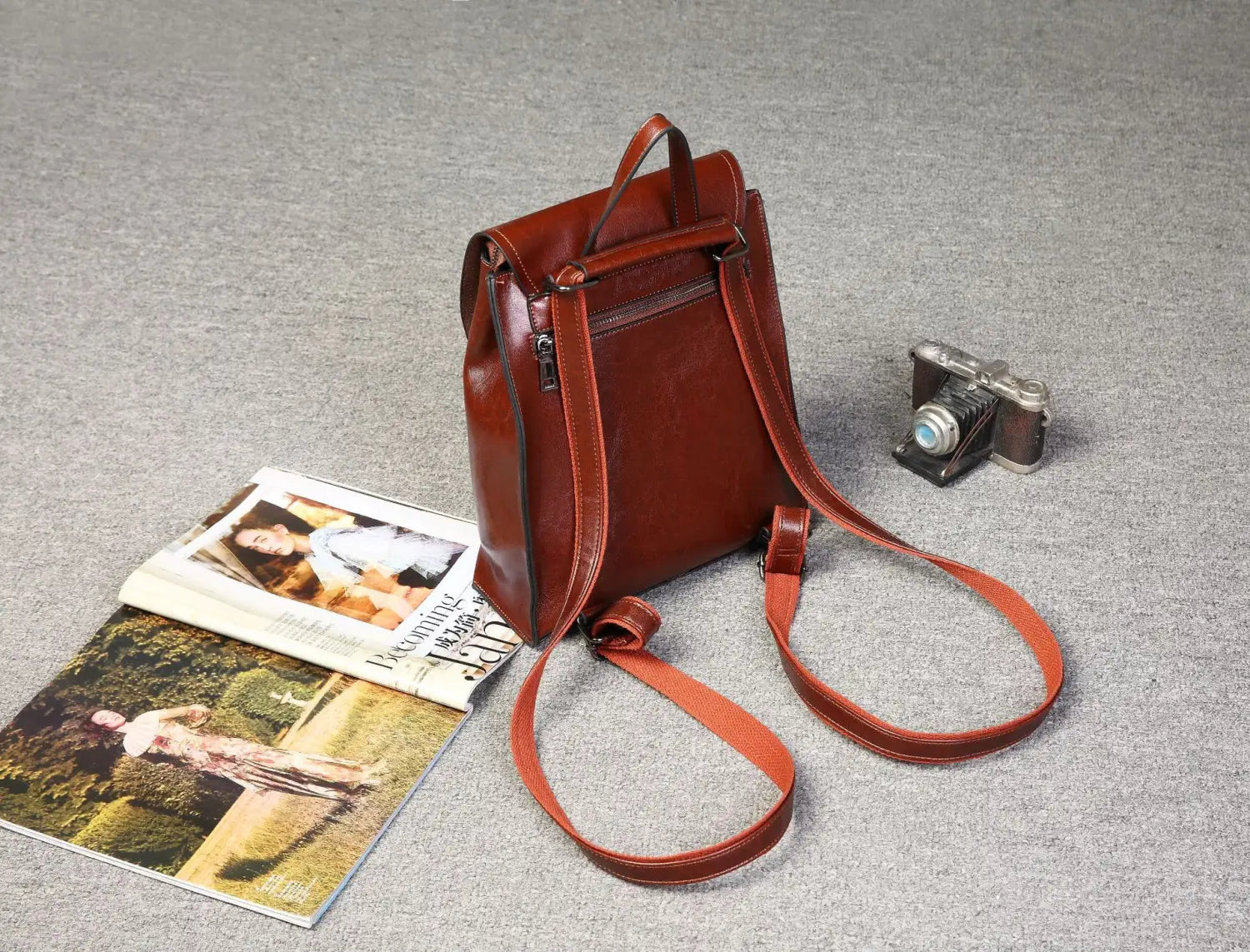 Una mochila bandolera de cuero marrón intensa con correas ajustables y cierre frontal con cremallera, que muestra un diseño de moda retro.