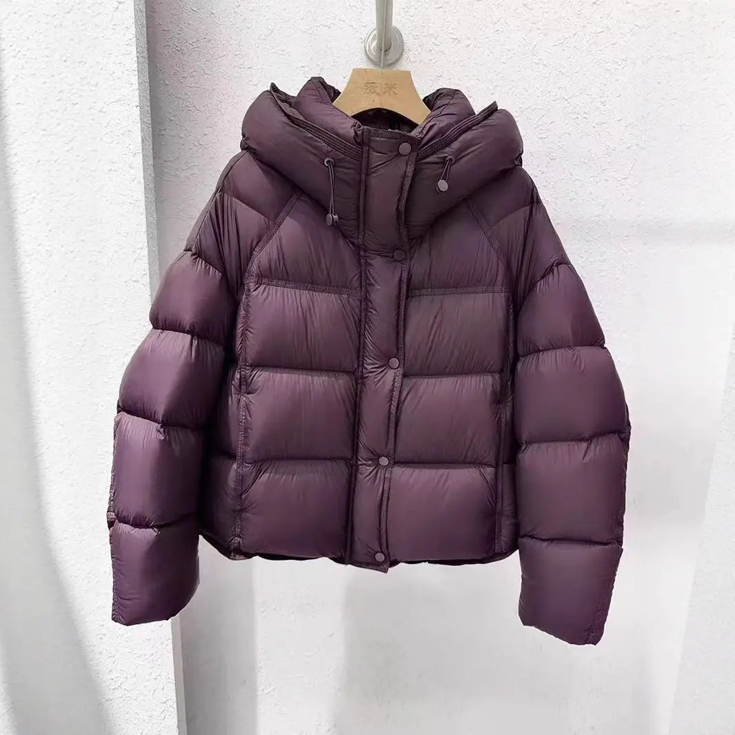 Una chaqueta acolchada de plumón morada y suave para invierno con capucha y cierre con botones para mujer