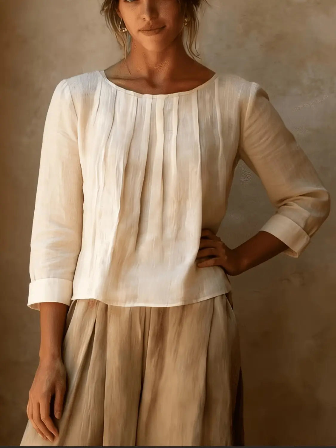 Une blouse ample en lin et coton pour femmes, blanc cassé, avec un devant plissé et des manches à la longueur trois-quarts.