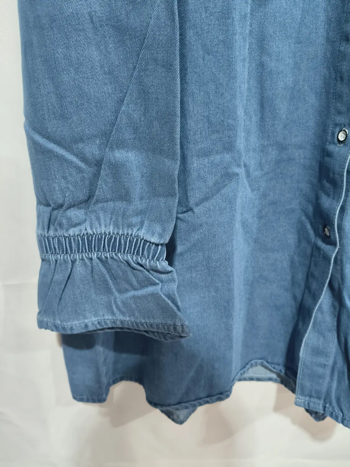 Ein weites Langarm-Jeanshemdkleid in Blau im A-Linien-Schnitt, mit entspannter Passform, mit langen Ärmeln, endend in elastischen Bündchen, sowie dezenten Rüschen.