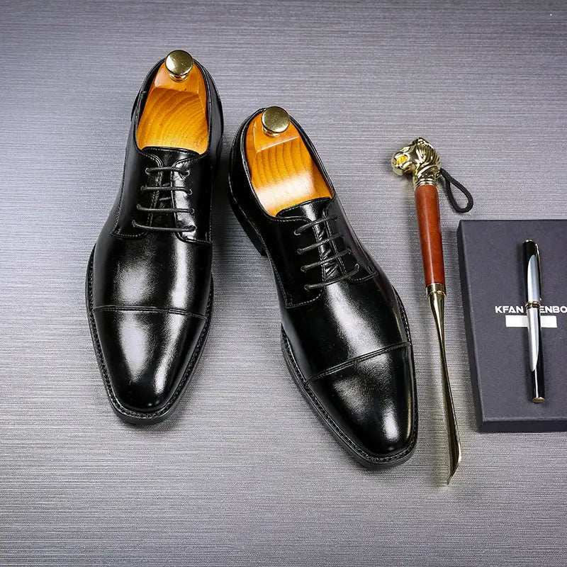 Herren-Businessschuhe im britischen Stil mit spitz zulaufender Zehenpartie aus Kunstleder in Schwarz, mit polierter Oberfläche und kontrastierender beiger Innenfutterausstattung.