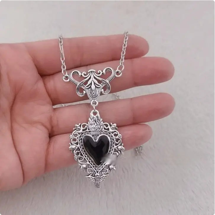 Vintage silver filigree heart pendant necklace featuring a black onyx stone centerpiece.