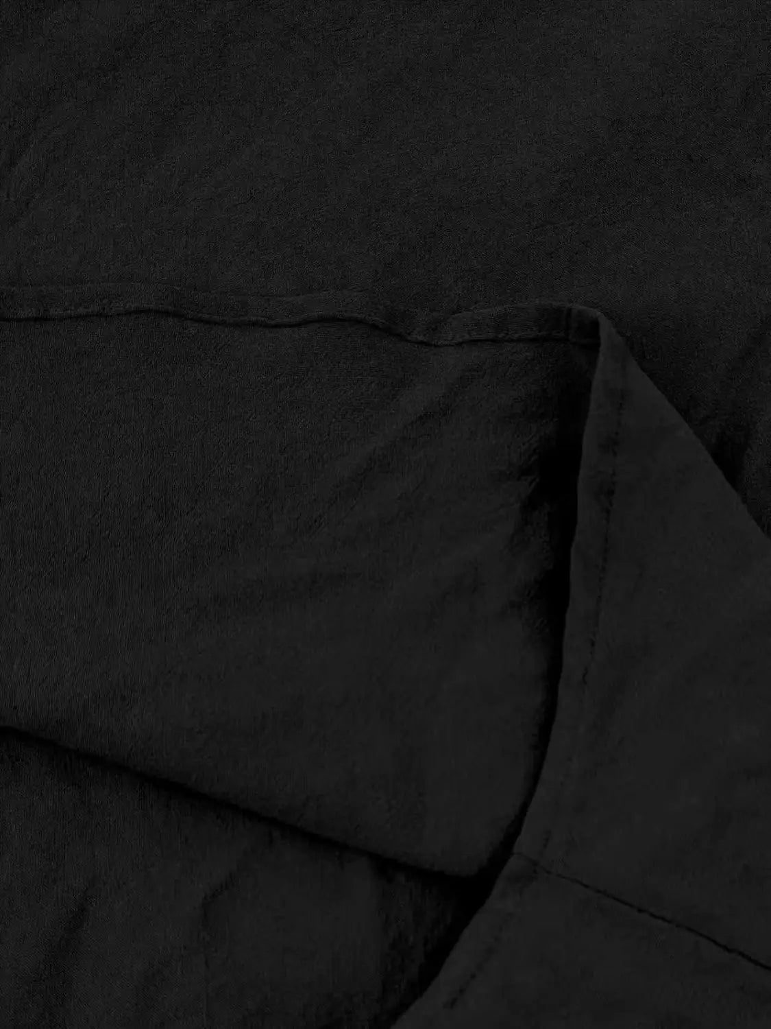 Schwarzer, strukturierter Baumwoll-Leinenstoff mit weichen Falten und dezenten Stickdetails eines Herren-Cotton-Leinenhemds mit Kordelzug.