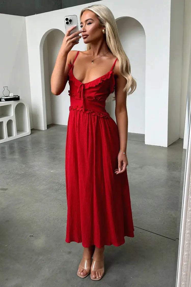 A vibrant red sleeveless flowing maxi vacation dress with delicate ruffled straps and a gathered waist.