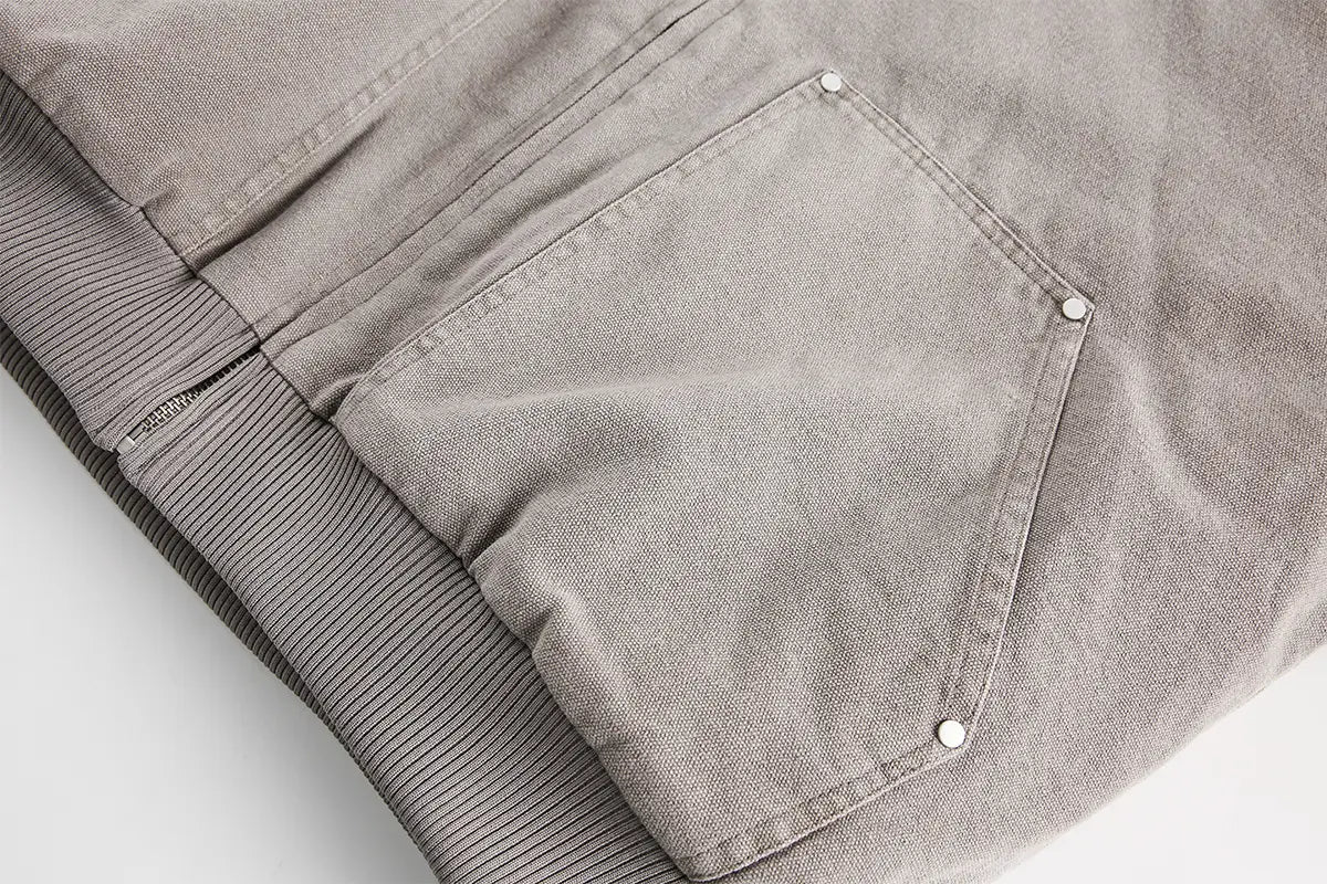 Bolsillo de mezclilla gris con cierres mediante botones blancos y forro interior acanalado, en un abrigo acolchado de invierno de algodón con forro de piel sintética para hombre y mujer.