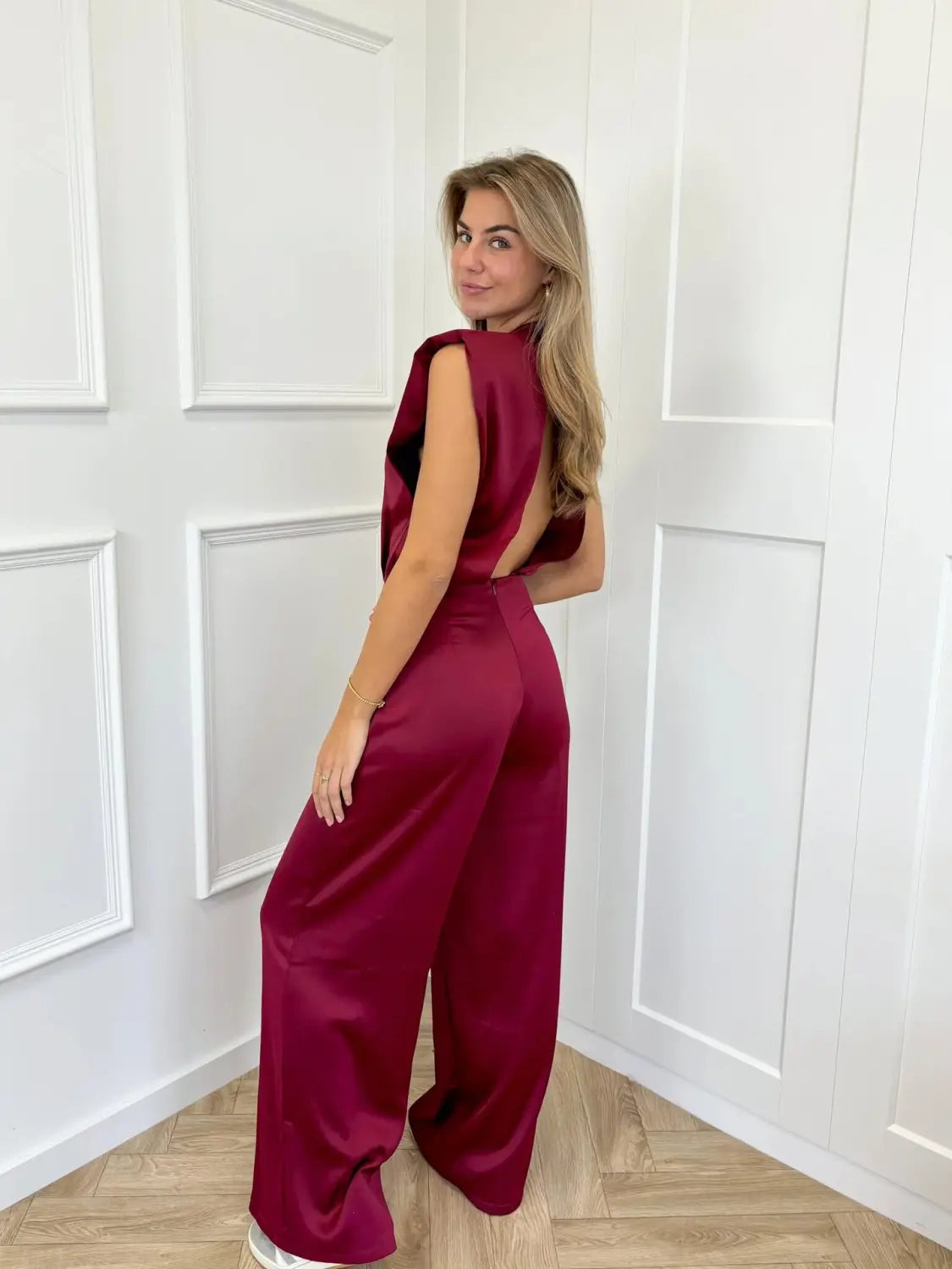 a sleek satin-like burgundy backless evening dress jumpsuit with a wide-leg silhouette and straight pants shown from the back side