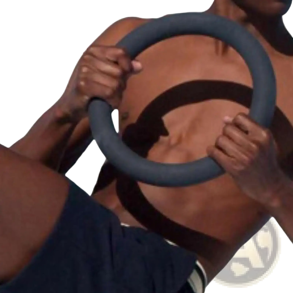 Dark gray padded 5lb weighted fitness ring held by a person designed for Pilates and strength training