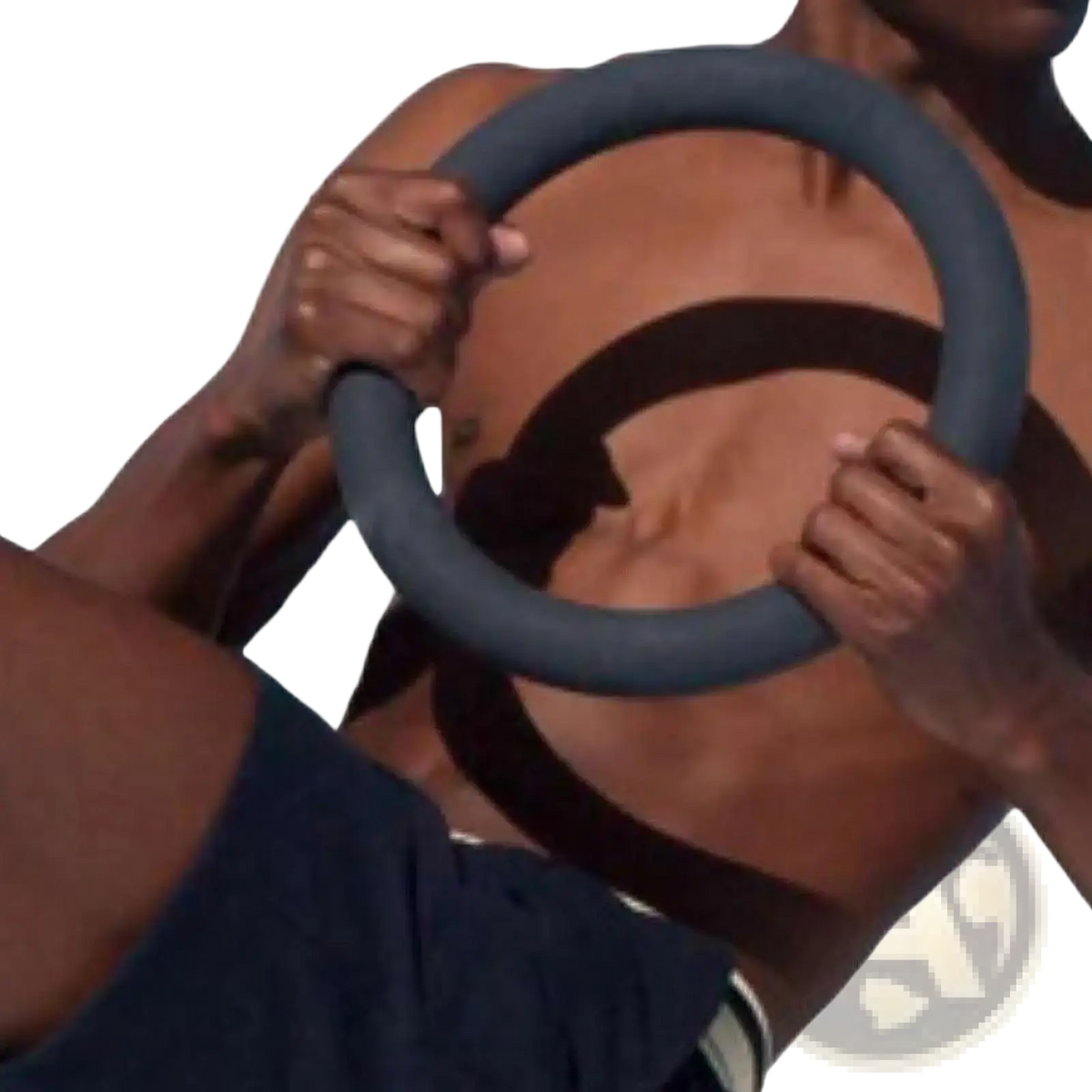Dark gray padded 5lb weighted fitness ring held by a person designed for Pilates and strength training