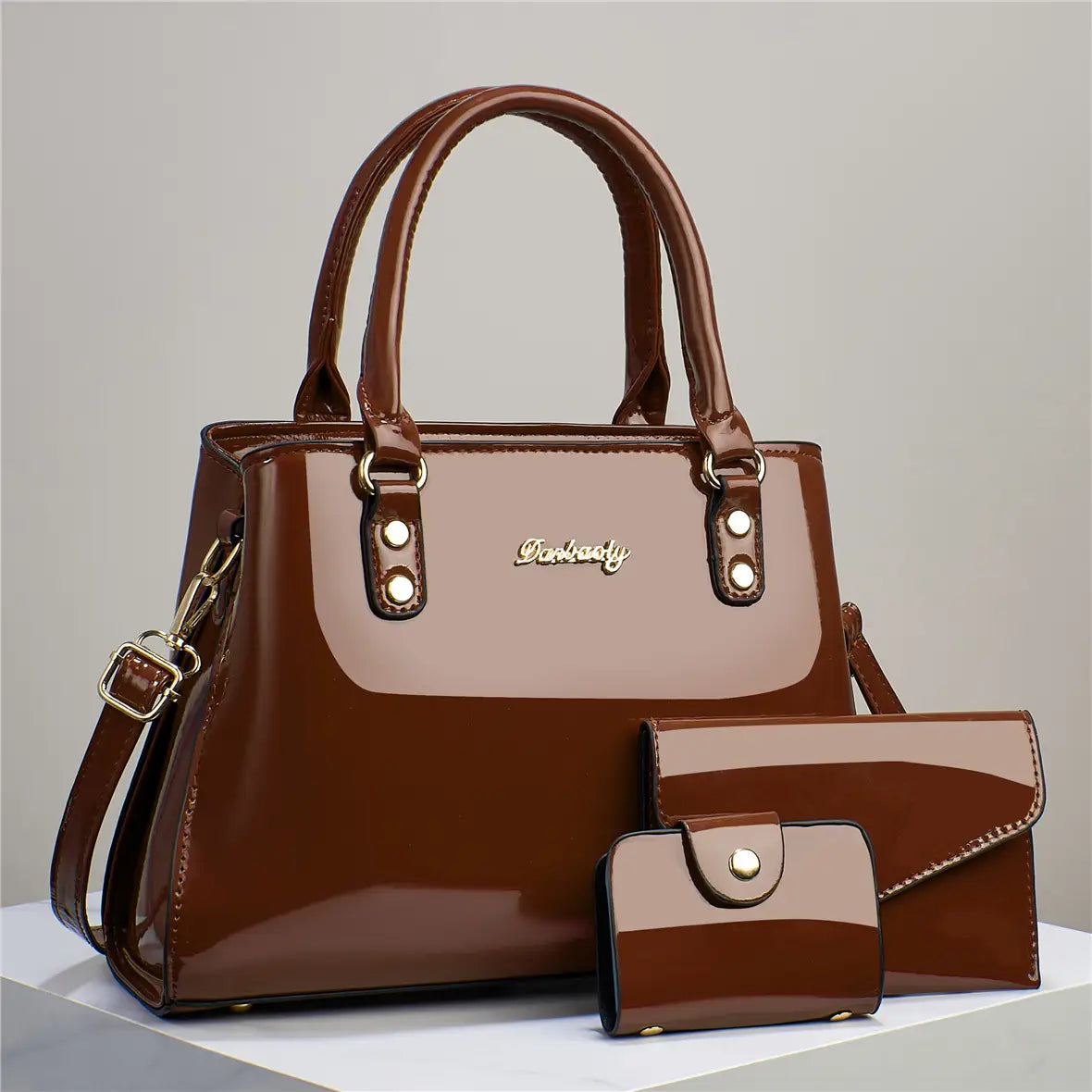 Glossy patent leather 3-piece handbag and wallet set featuring a brown glossy handbag with matching wallet and clutch in a two-tone design with lighter brown accents and gold-toned hardware.