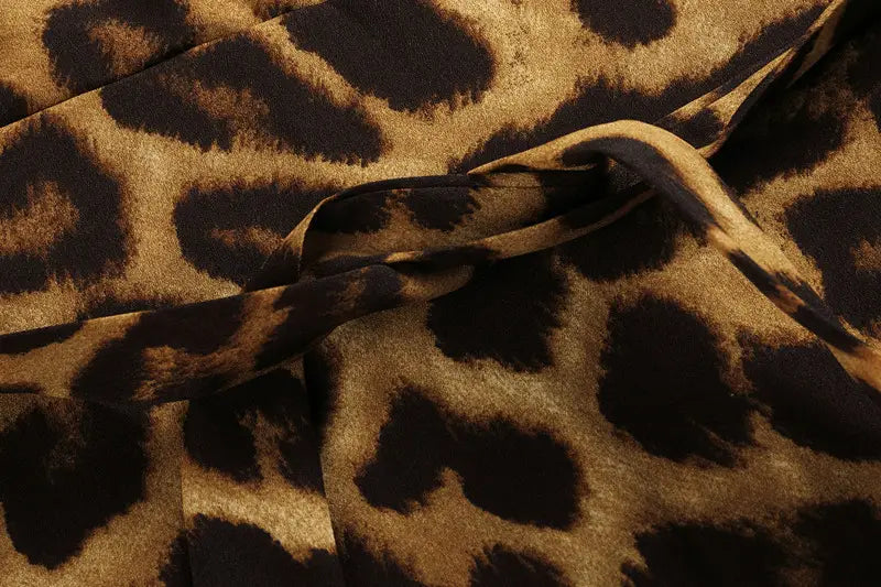 A leopard print v neck long sleeve chiffon wrap dress featuring soft flowing fabric with a bold leopard print pattern in rich brown and black tones.