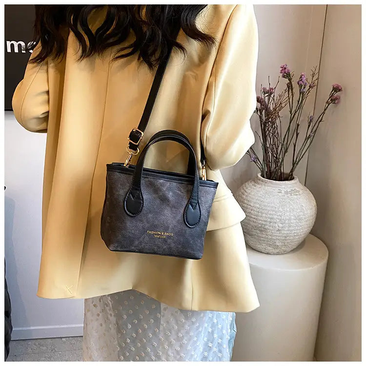 Black textured mini retro bucket bag made of canvas with gold-tone hardware and a subtle logo on the front for shoulder use