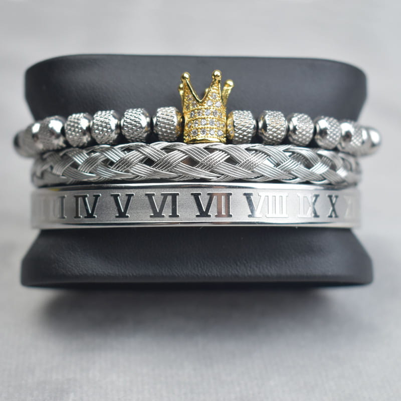 Stacked silver and gold-toned Crown Royal diamond beaded bracelet set with braided bands featuring textured beads roman numerals and a central golden crown charm.
