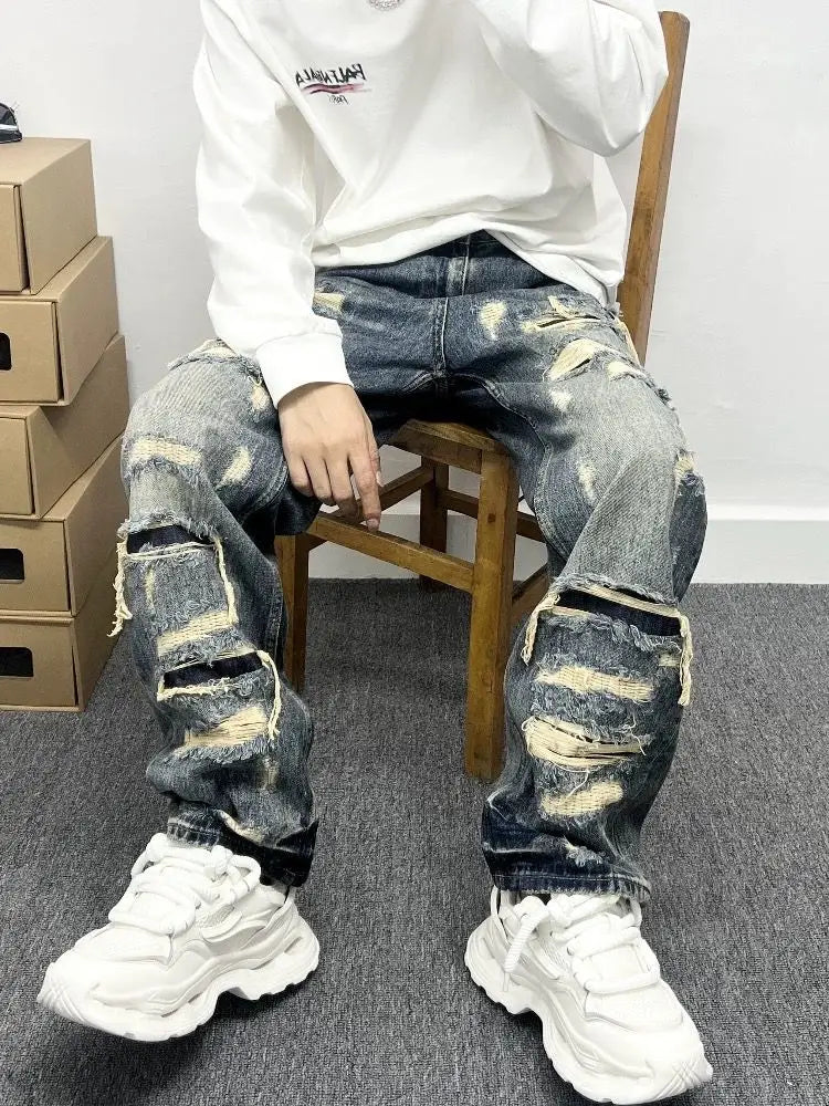 Men’s light blue distressed ripped patch denim jeans made of dark-wash denim with frayed and ripped details.