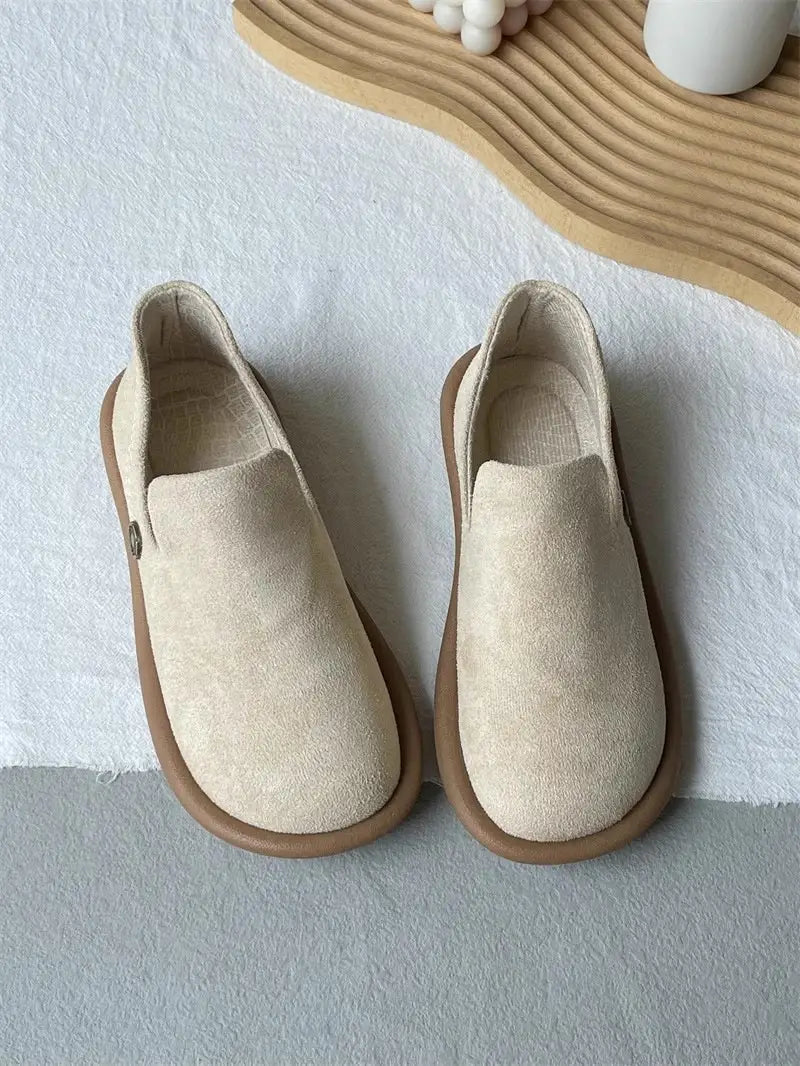 Beige Veloursleder-Slipper im Vintage-British-Stil mit niedrigem Absatz mit einer braun wirkenden Gummisohle.