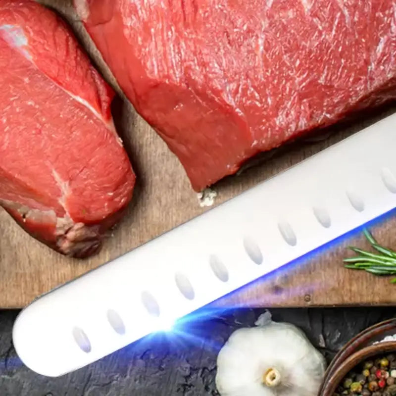 White ceramic chef knife with oval cutouts along the blade edge designed for meat and ham cutting.