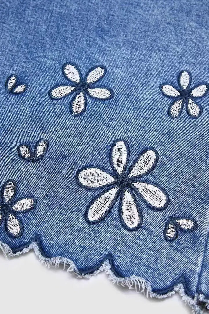 青色のデニムのフラワー刺繍クロップドジーンズ。白い花と、スカラップ仕立てのほつれ加工が施されています。