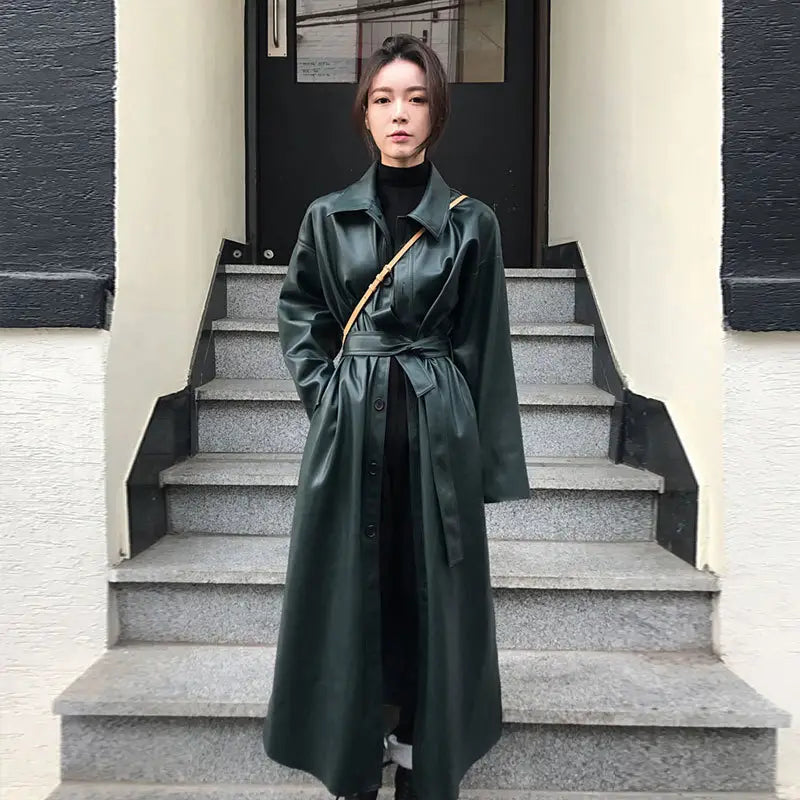 dark green faux leather trench coat with belted waist and long sleeves suitable as a windbreaker jacket