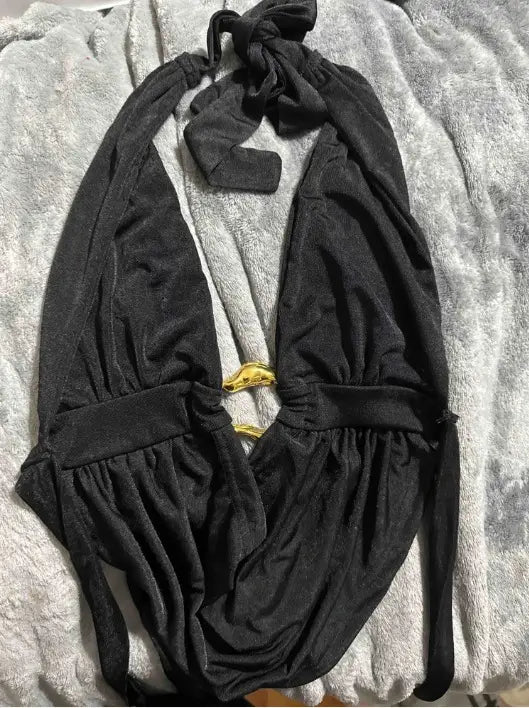 Black satin halter romper with faux leather shorts featuring a black halter neck top with a gold toned buckle and tied neck detail.
