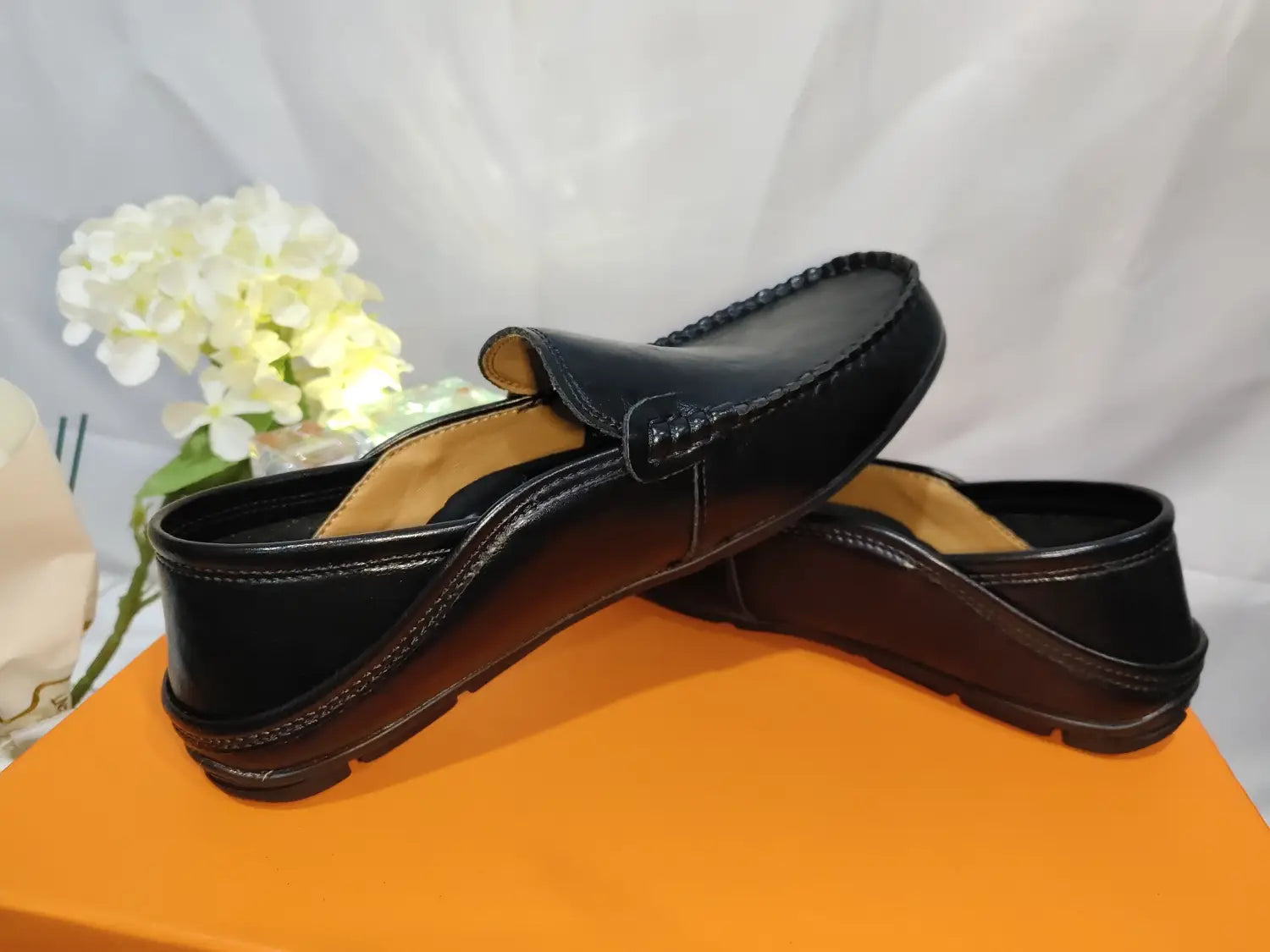 Mocasines tipo alpargata de cuero negro para hombre, con acabado brillante y detalles de costura, diseñados como zapatos de conducción casuales.