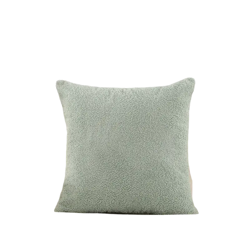 A 60x60cm cushion cover in light teal solid teddy velvet with a plush texture on a beige tufted sofa