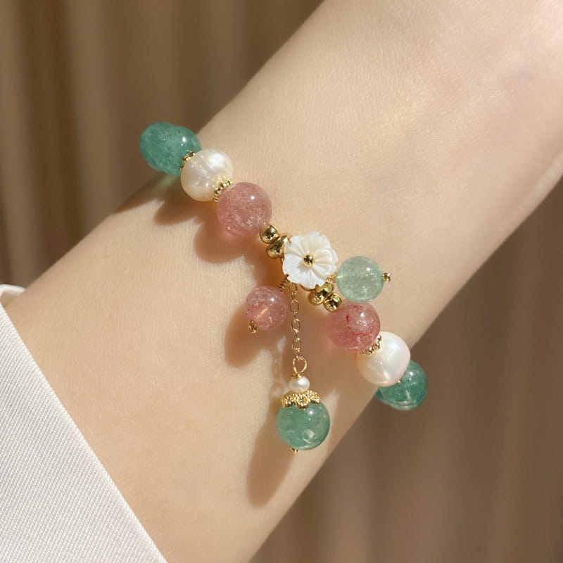 A delicate Korean floral green strawberry crystal beaded bracelet featuring pastel pink and teal gemstone beads, white pearl-like spheres, and a central floral charm suspended by gold-toned metal links.