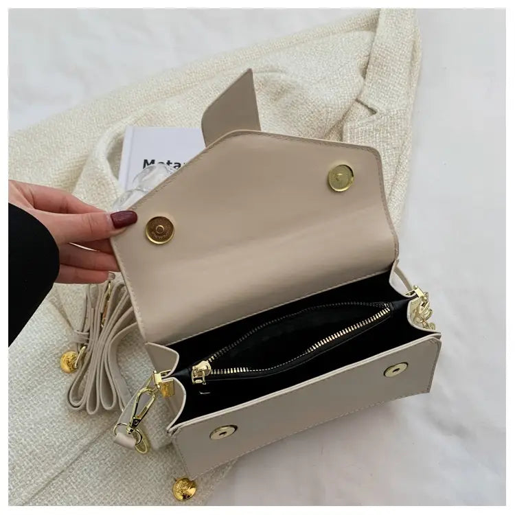 Beige faux leather monogram letter print crossbody messenger bag with gold-tone hardware and a detachable strap.