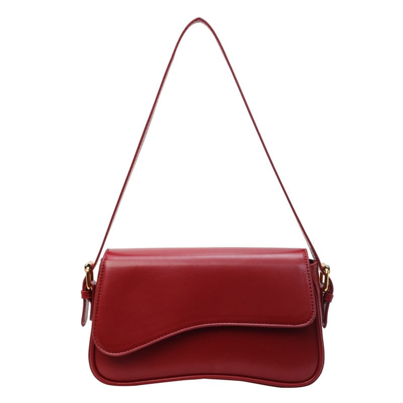 A sleek glossy red leather messenger bag with a curved flap and gold-tone hardware designed as a minimalist crossbody organ bag.