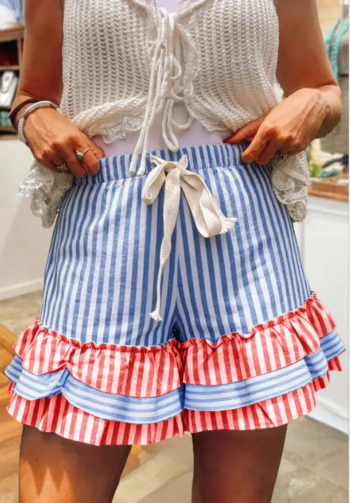 Blau-weiße gestreifte Shorts mit einem roten und blauen gerafften Saum, kombiniert mit einem Karomosaik-A-Linien-Rock, von hinten gezeigt.