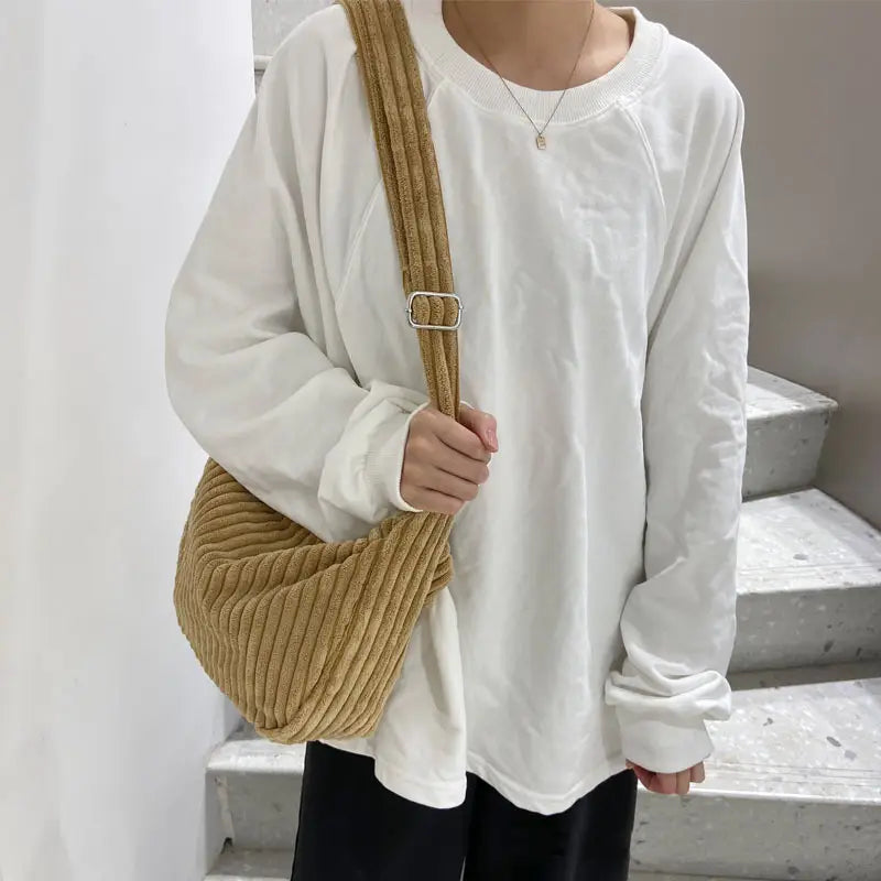 Tan corduroy crossbody shoulder bag with adjustable strap featuring a ribbed texture and silver buckle.