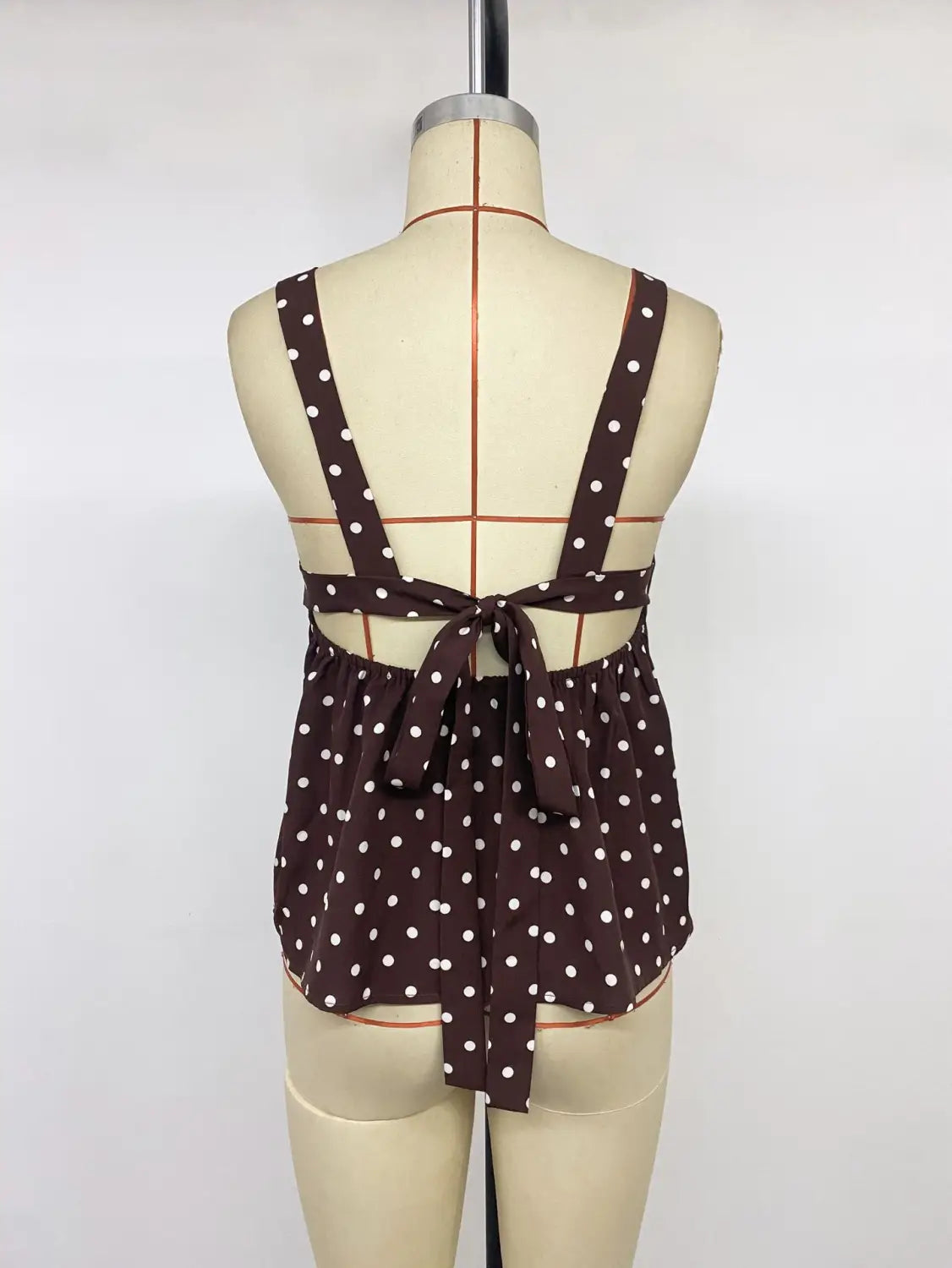 Brown polka dot peplum camisole with an adjustable halter top design and tied-back detail shown from the back side.