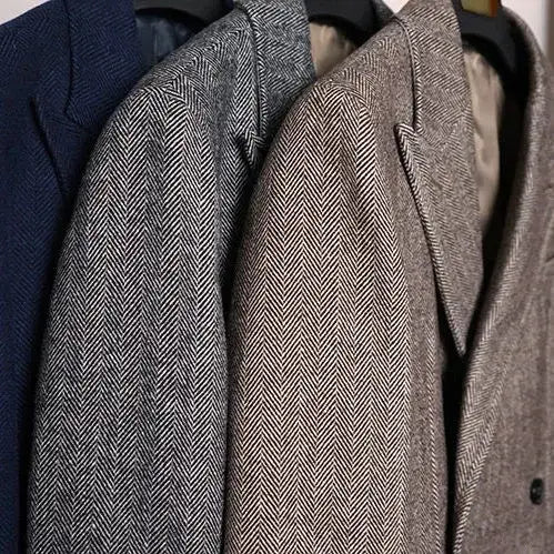 Three British vintage woolen coat slim tweed blazers in navy gray and beige herringbone pattern hang neatly on black hangers.