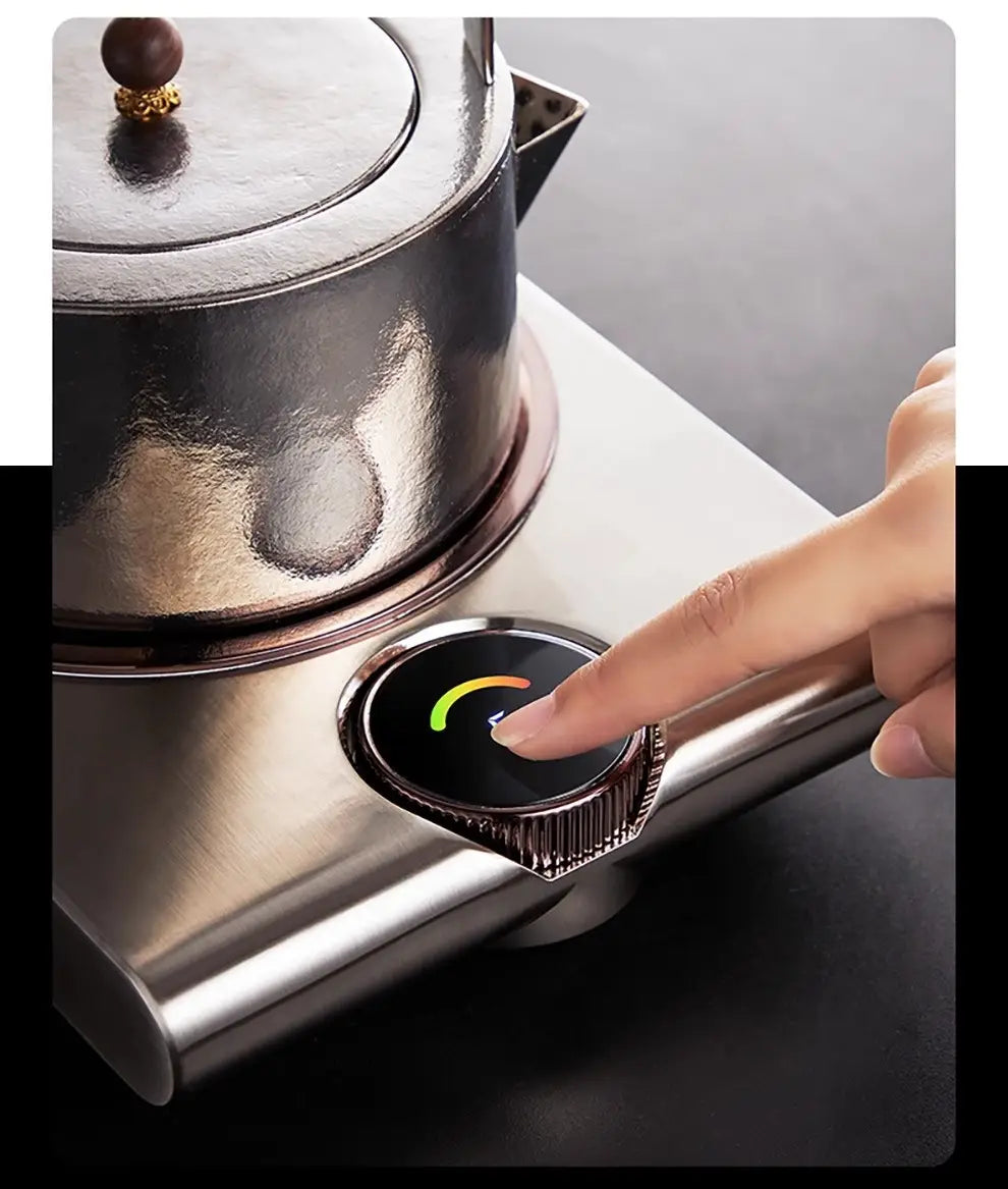 A sleek stainless steel electric kettle with a polished metallic finish and gold-accented lid knob sits atop its matching base unit in the electric ceramic stove 1000w tea cooker kettle.