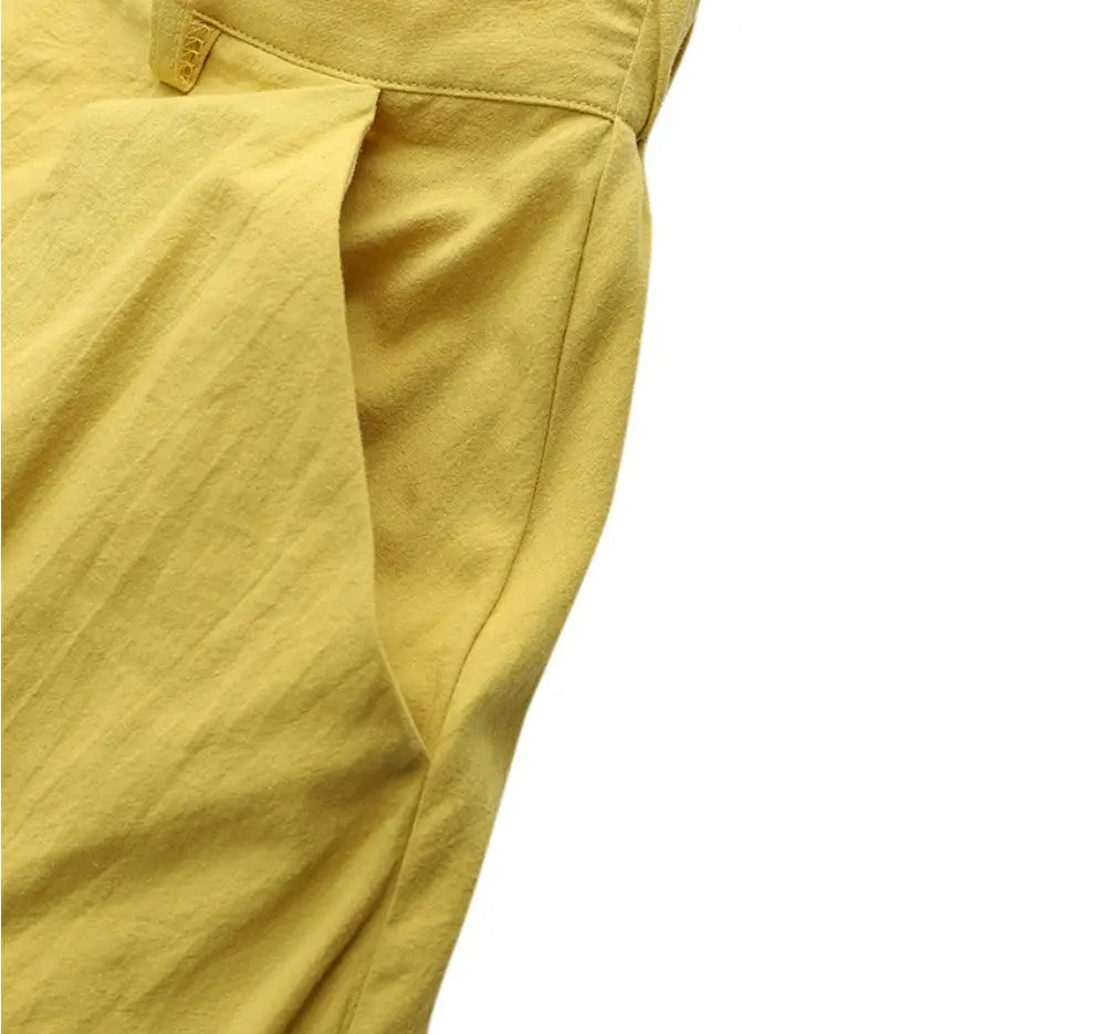 Pantalon en lin jaune au toucher légèrement texturé et à la couture proprement travaillée, complétant le produit de jupe longue maxi en satin taille haute au tombé fluide.