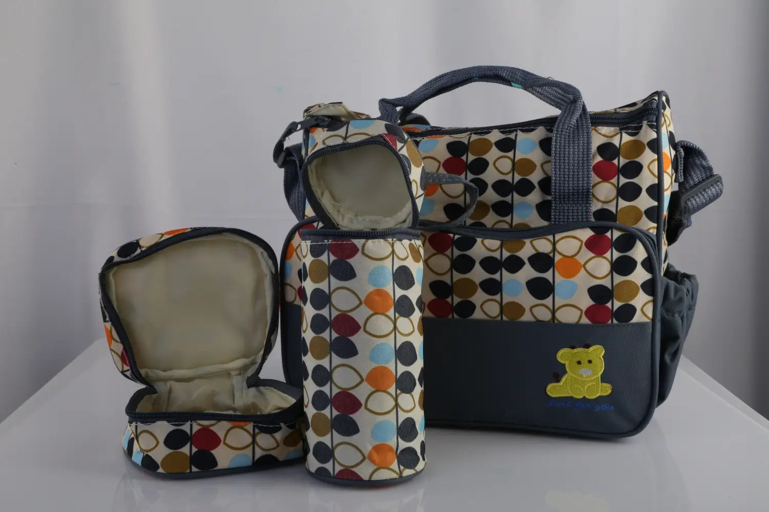 Multicolored polka-dot baby diaper bag with a navy blue base and yellow bear appliqué from the 5-piece floral water-resistant baby diaper bag travel set.