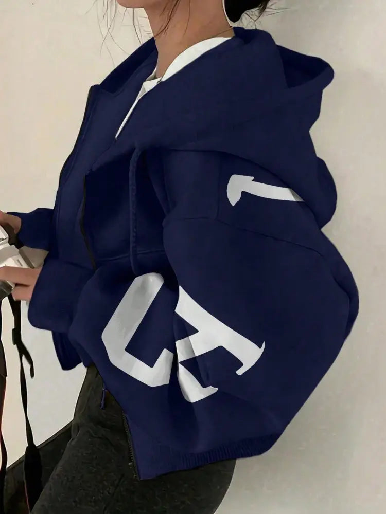 Sweat-shirt à capuche zippé imprimé graphique bleu marine, avec un lettrage blanc audacieux sur les manches.
