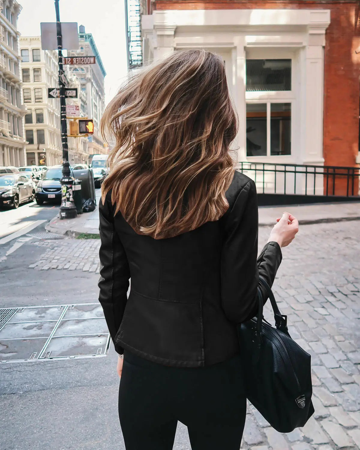 black leather shoulder bag with a subtle logo on the front paired with women’s faux leather bomber jacket urban casual coat for a stylish look