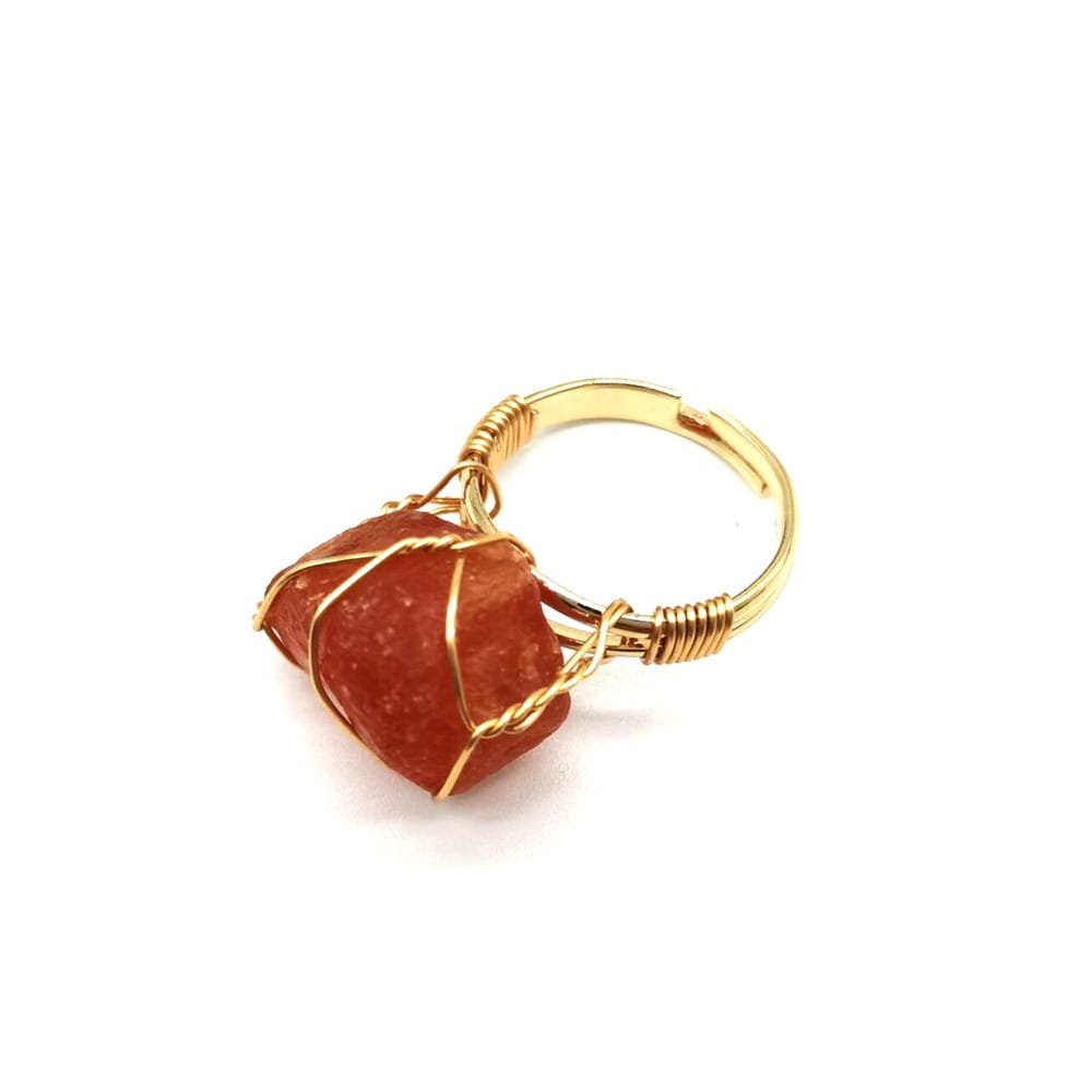 Handcrafted adjustable gold wire wrapped ring featuring a rough orange red carnelian gemstone.